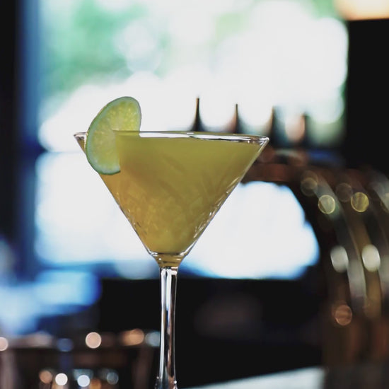 Video: Barkeeper bereitet den Cocktail „The Lion Gin“ mit Limette zu und serviert ihn in einem Martini-Glas mit Limette.