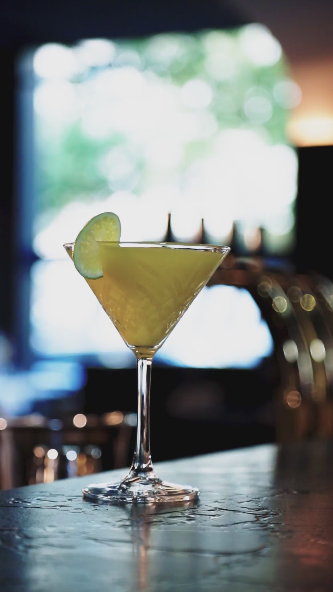 Video: Barkeeper bereitet den Cocktail „The Lion Gin“ mit Limette zu und serviert ihn in einem Martini-Glas mit Limette.
